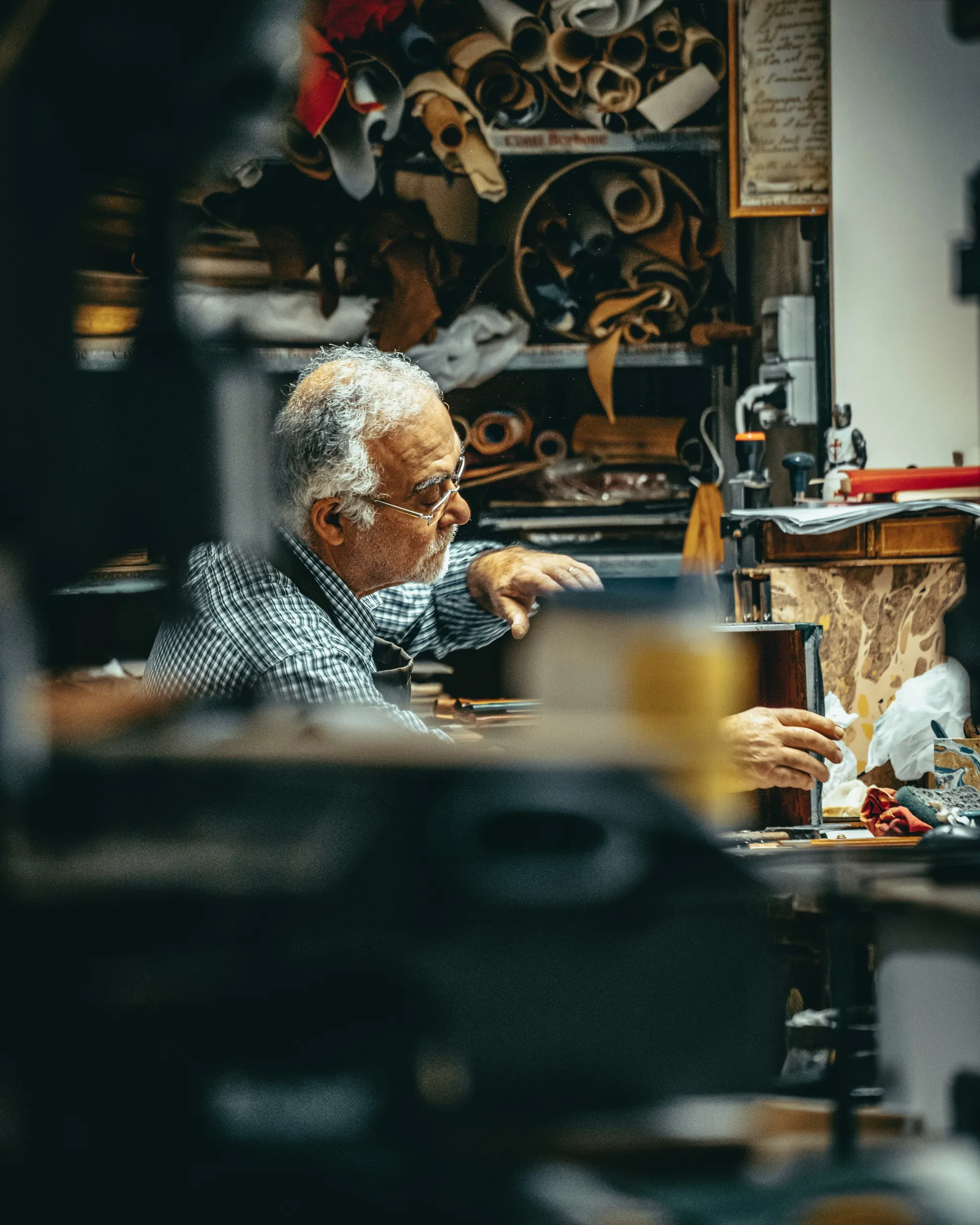 Ein älterer Handwerksmeister arbeitet konzentriert in seiner Werkstatt